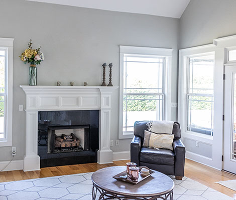 room with light gray walls, fireplace, table, and armchair