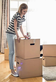 woman taping up cardboard boxes